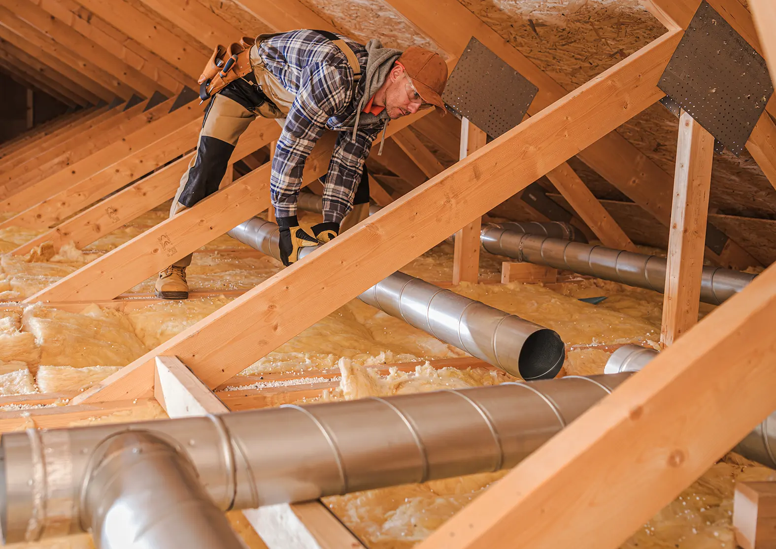 Contractor installing HVAC ducts in the attic of a residence.